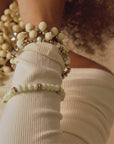 Stacked ivory and gold stretch bracelets with creamy beads and metallic accents in a soft honey toned design.