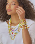 Stacked pearl and colorful bead stretch bracelets with gold accents and playful charms designed for layered wrist styling