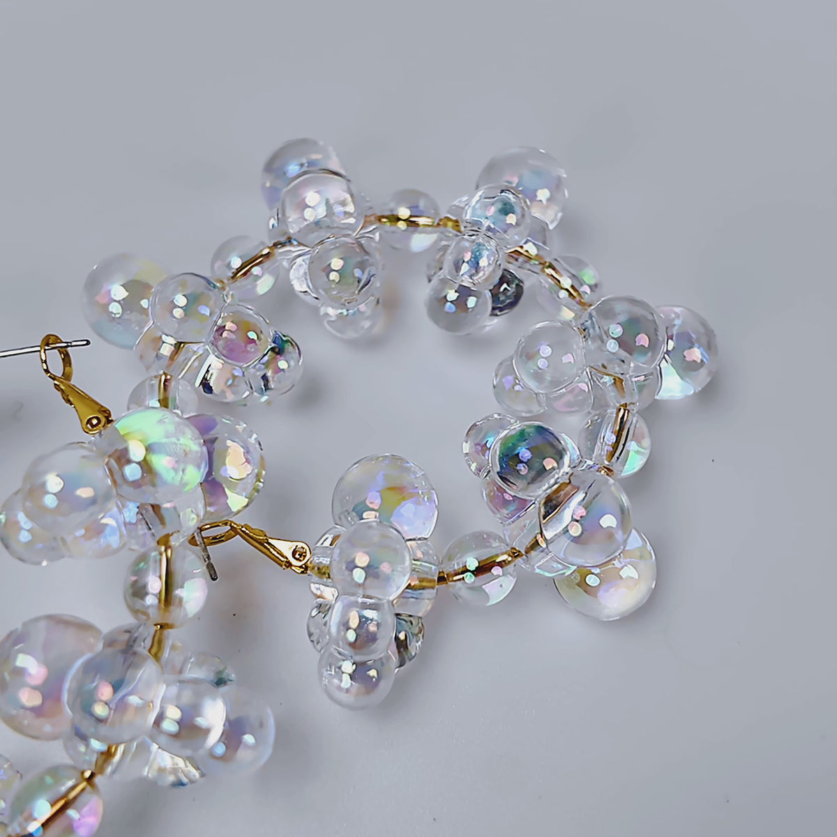 Close up of Alana Cloud Bubble Hoops showing translucent clustered bubbles with a rainbow reflective finish.
