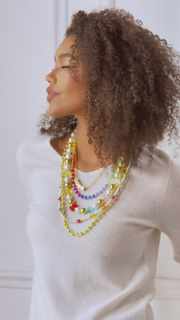 Layered 18k gold necklace with pearls, colorful beads, and playful teddy bear charms designed for fun luxury styling