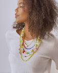Layered 18k gold necklace with pearls, colorful beads, and playful teddy bear charms designed for fun luxury styling