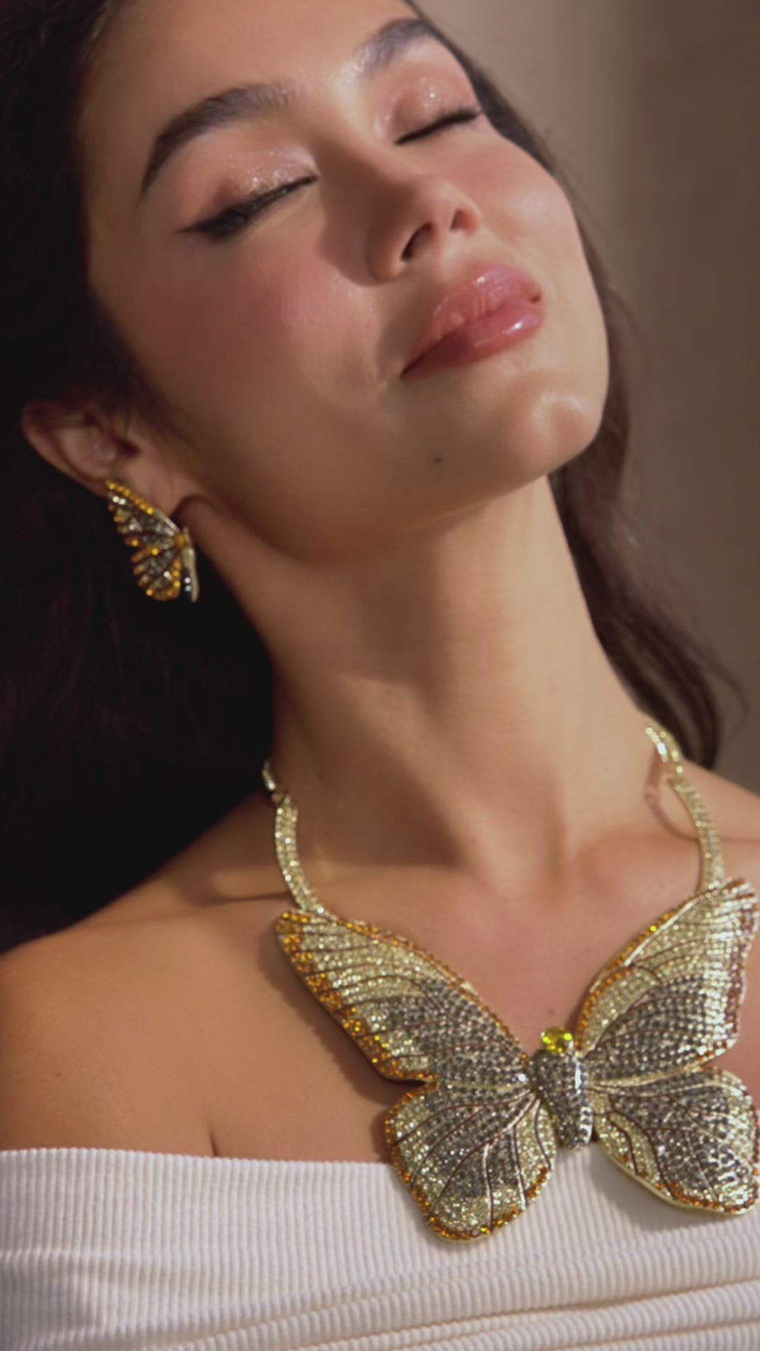 Gold butterfly stud earrings with champagne and smoky crystals in a delicate yet radiant design.