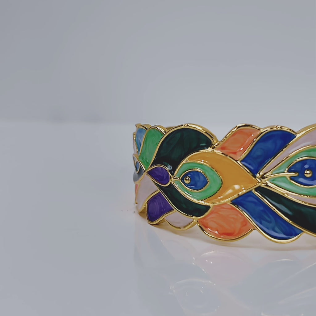 Sculptural peacock inspired cuff bracelet with colorful hand painted enamel style detailing and Gold tone finish.