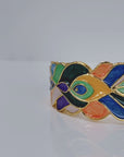Sculptural peacock inspired cuff bracelet with colorful hand painted enamel style detailing and Gold tone finish.