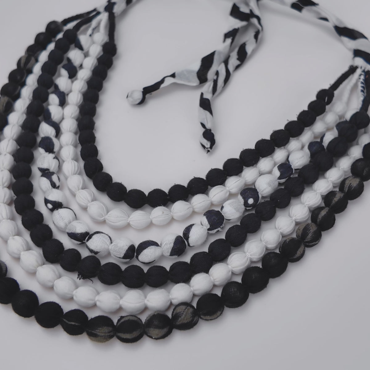 Close view of Kenza Cloth Bead Bib featuring mixed black and white textile covered beads.