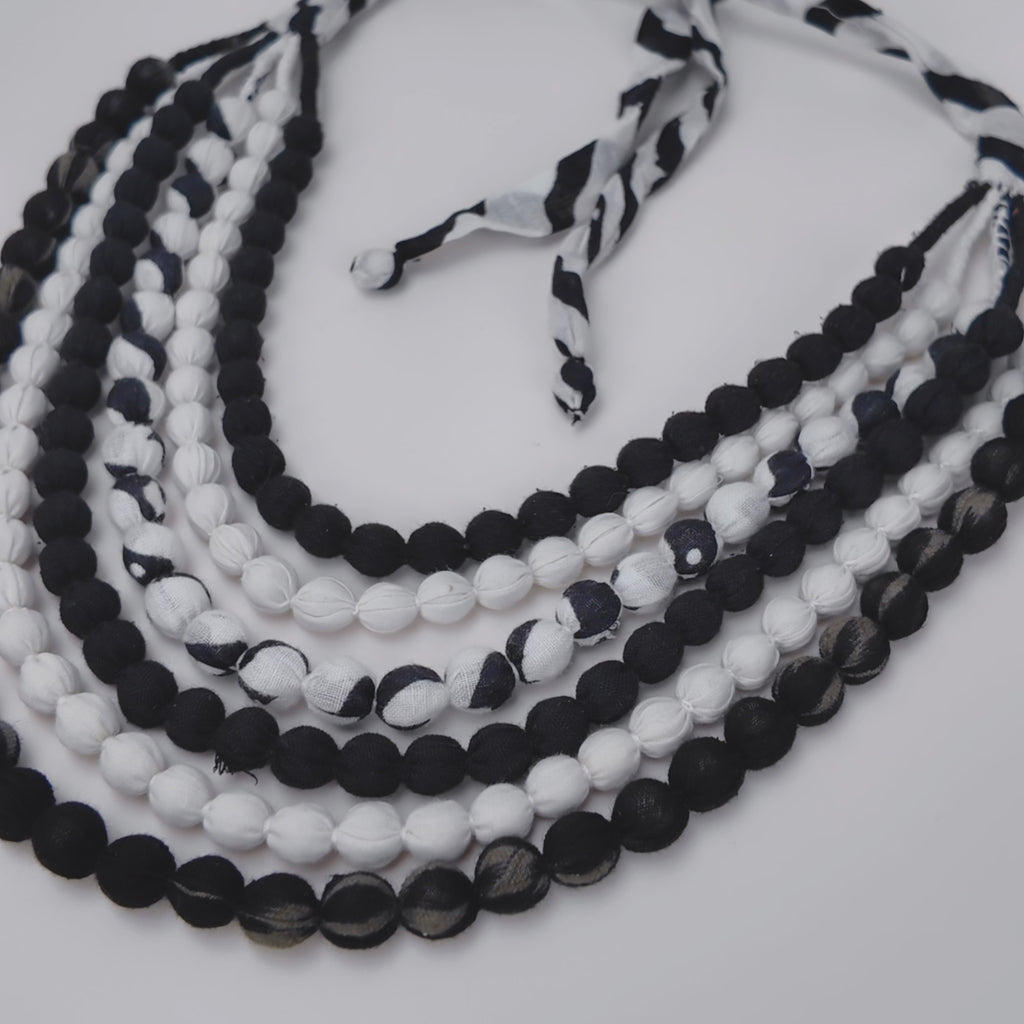 Close view of Kenza Cloth Bead Bib featuring mixed black and white textile covered beads.