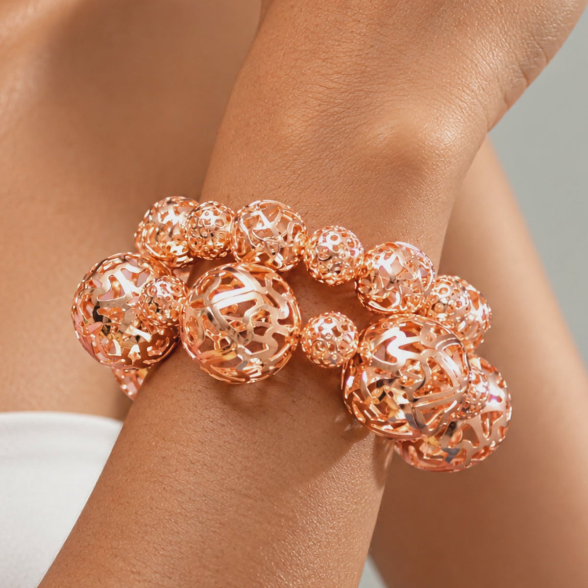 Two piece rose gold stretch bracelet set featuring intricate cutout sphere detailing.