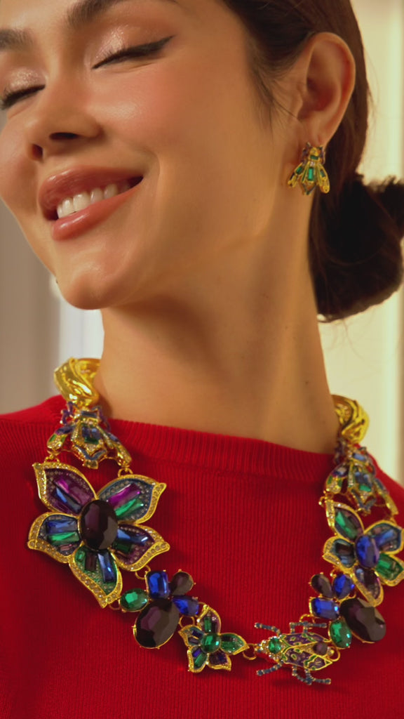 Gold statement beetle earrings with amethyst, blue, and green crystals featuring intricate detailing and colorful enamel accents.