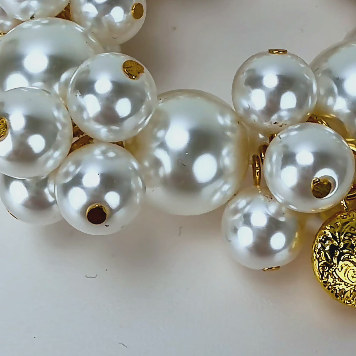 Close up of Amora Pearl Heart Bracelet featuring luminous pearl clusters and embossed gold heart details.