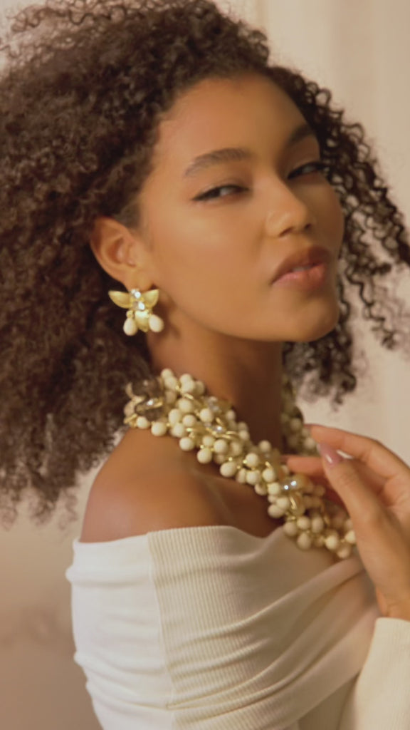 Gold floral dangle earrings with crystal centers and soft ivory drop accents in a honey toned elegant design.