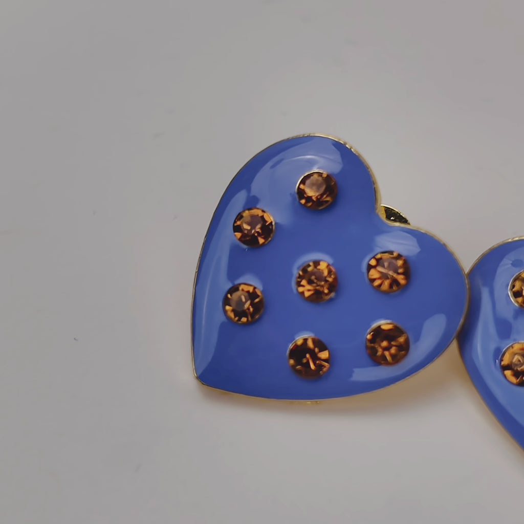 Blue heart stud earrings featuring a glossy finish, warm golden crystals and polished gold detailing.