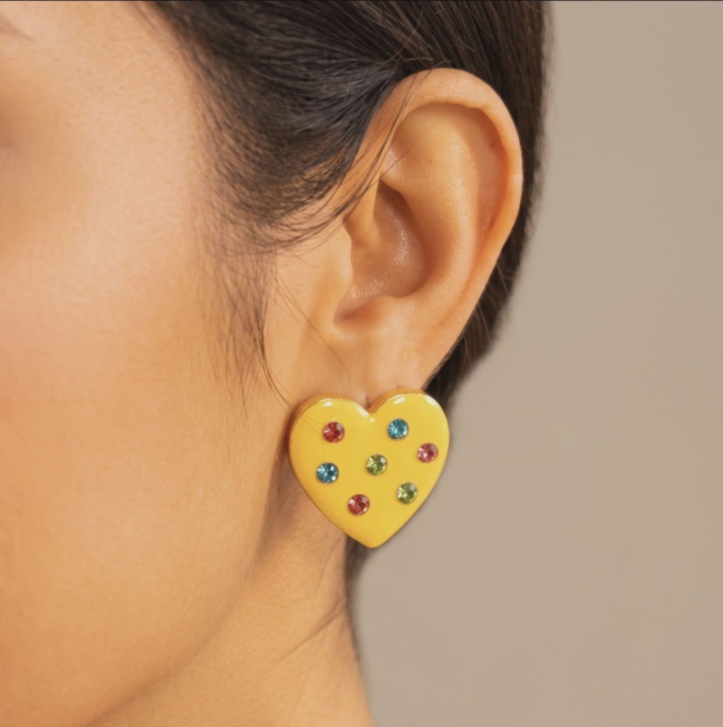  Colorful heart stud earrings featuring a yellow finish, red, blue and green crystals, and polished gold detailing.