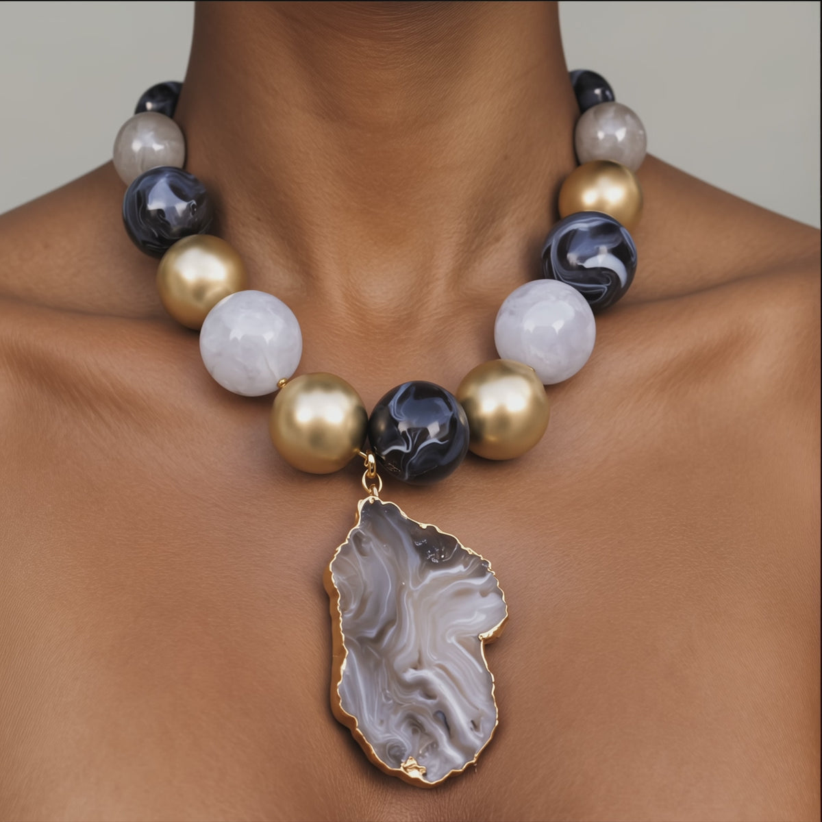 Natural stone statement necklace featuring a gray and black agate slice edged in a Gold tone finish.