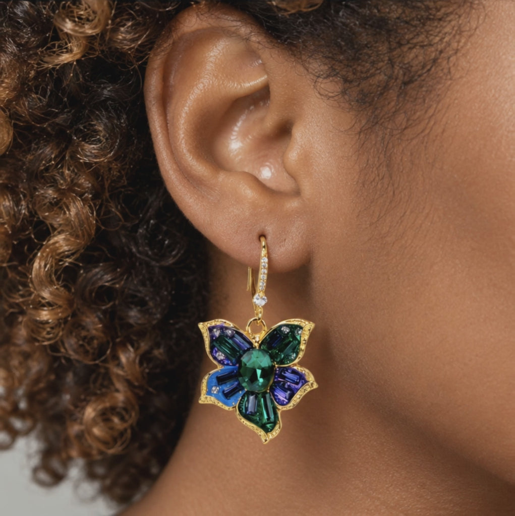Close up of Valerie Miss Beasley earrings showcasing green, blue and purple faceted crystals with sparkling borders.