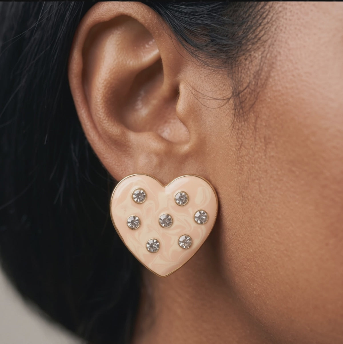 Close up of Lovebug 18K Stud showing a dimensional cream heart with seven sparkling crystal accents.