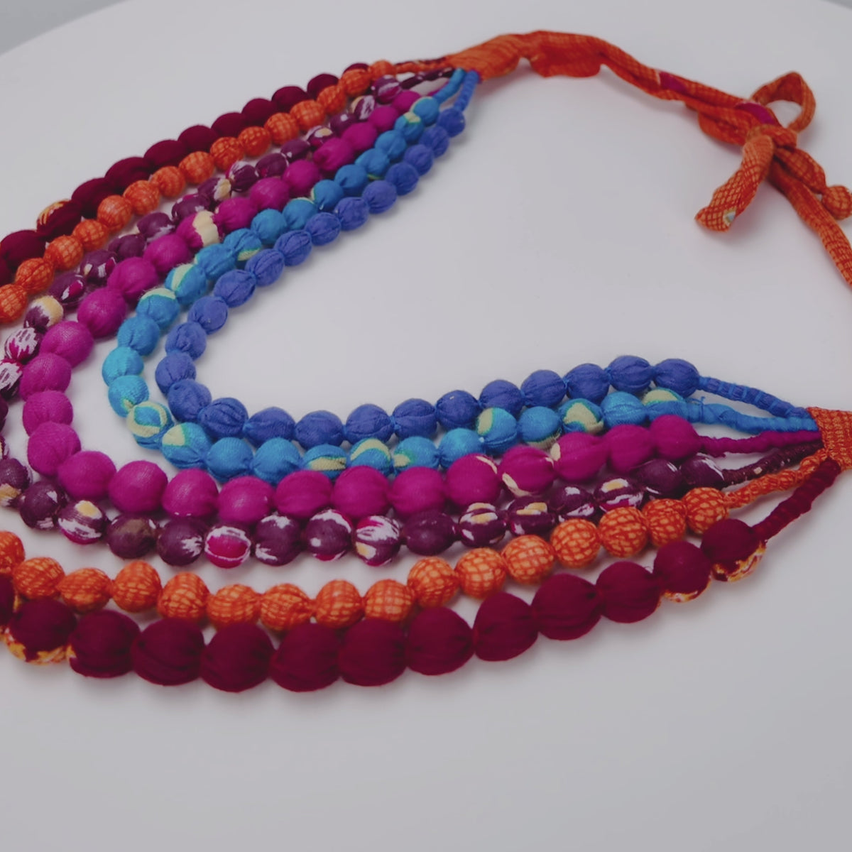 Close view of Kenza Cloth Bead Bib featuring saturated multicolor beads in mixed solid and patterned fabrics.