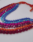 Close view of Kenza Cloth Bead Bib featuring saturated multicolor beads in mixed solid and patterned fabrics.