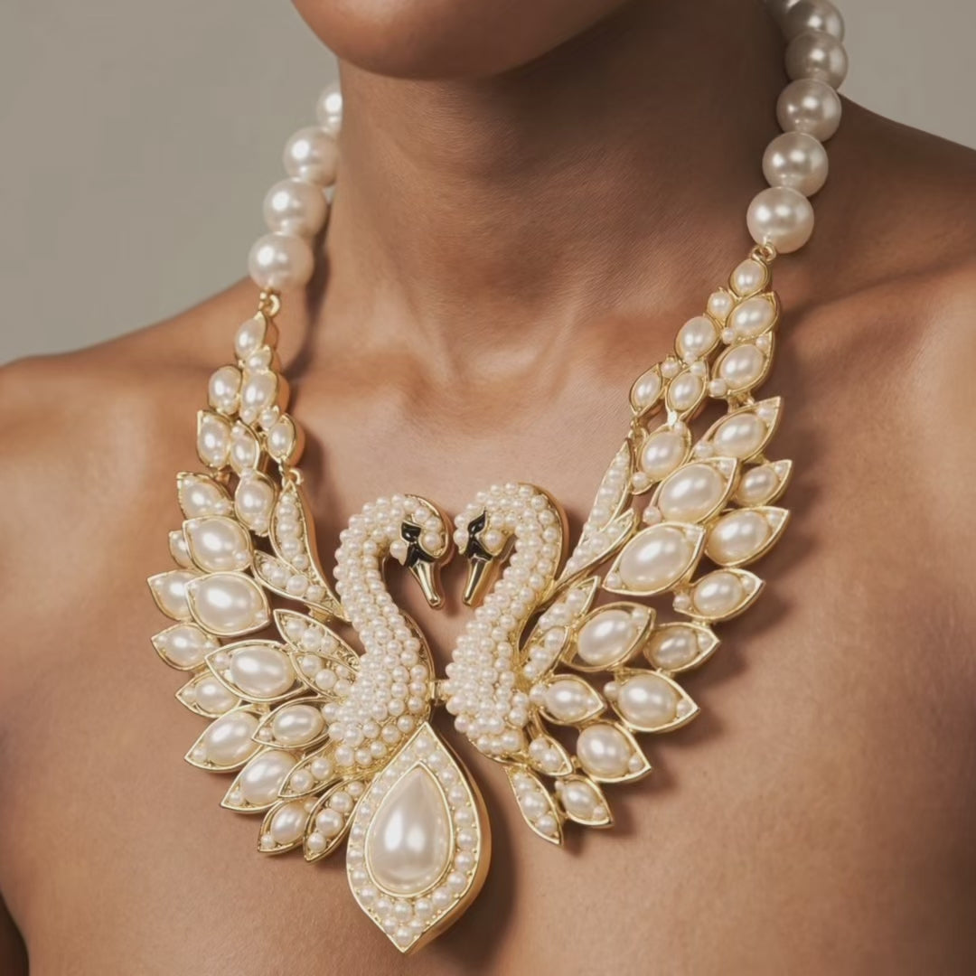 gold tone swan bib necklace with crystal detailing, pearl embellished wings, and a large teardrop pearl centerpiece.