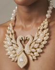 gold tone swan bib necklace with crystal detailing, pearl embellished wings, and a large teardrop pearl centerpiece.