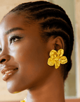 18k gold sculptural floral statement earrings inspired by wisteria blossoms with layered petals and faceted gold center worn on a woman’s ear