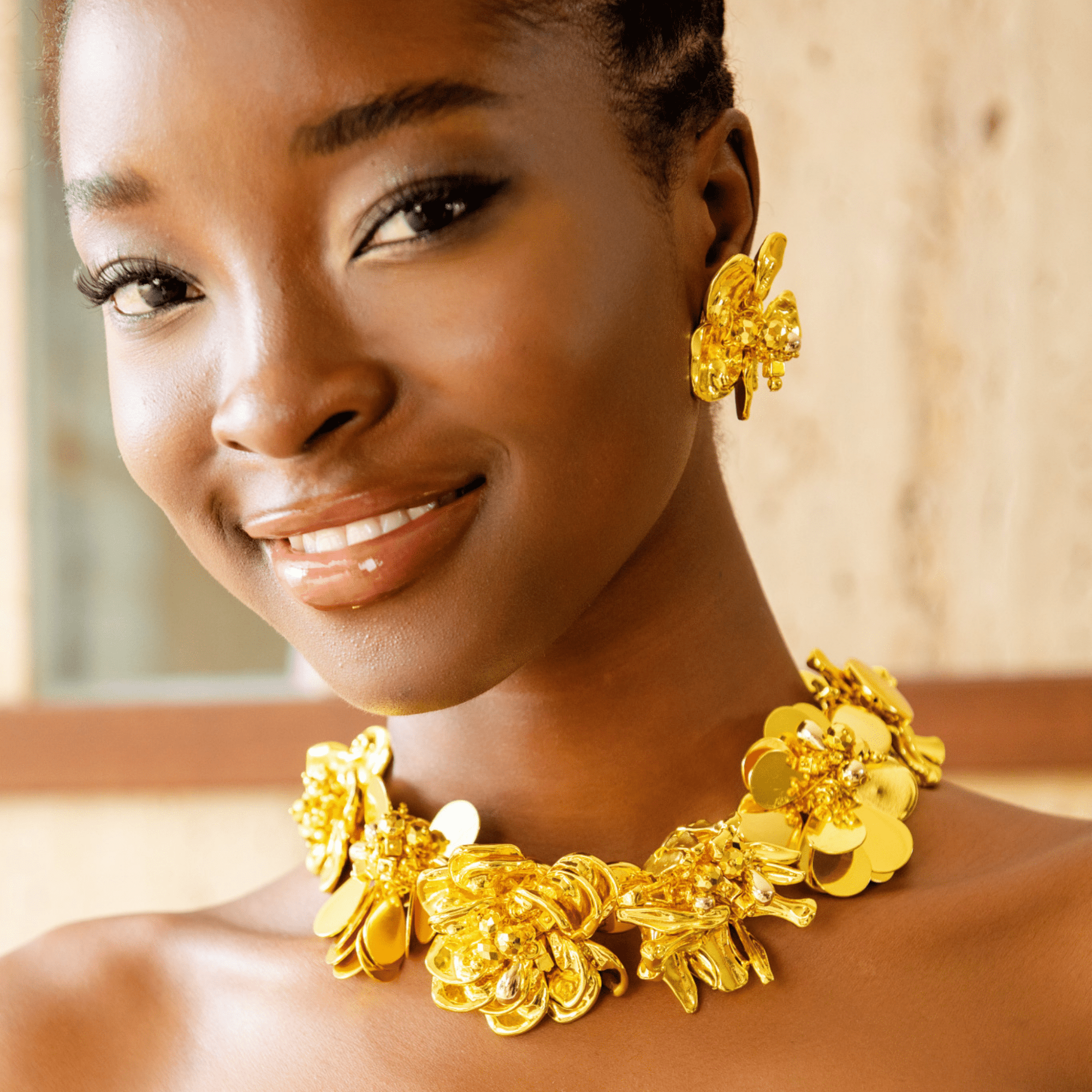 18k gold sculptural floral statement necklace with layered petals and reflective discs inspired by cascading wisteria blossoms worn on a woman's neckline