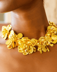 18k gold sculptural floral statement necklace with layered petals and reflective discs inspired by cascading wisteria blossoms worn on a woman's neckline