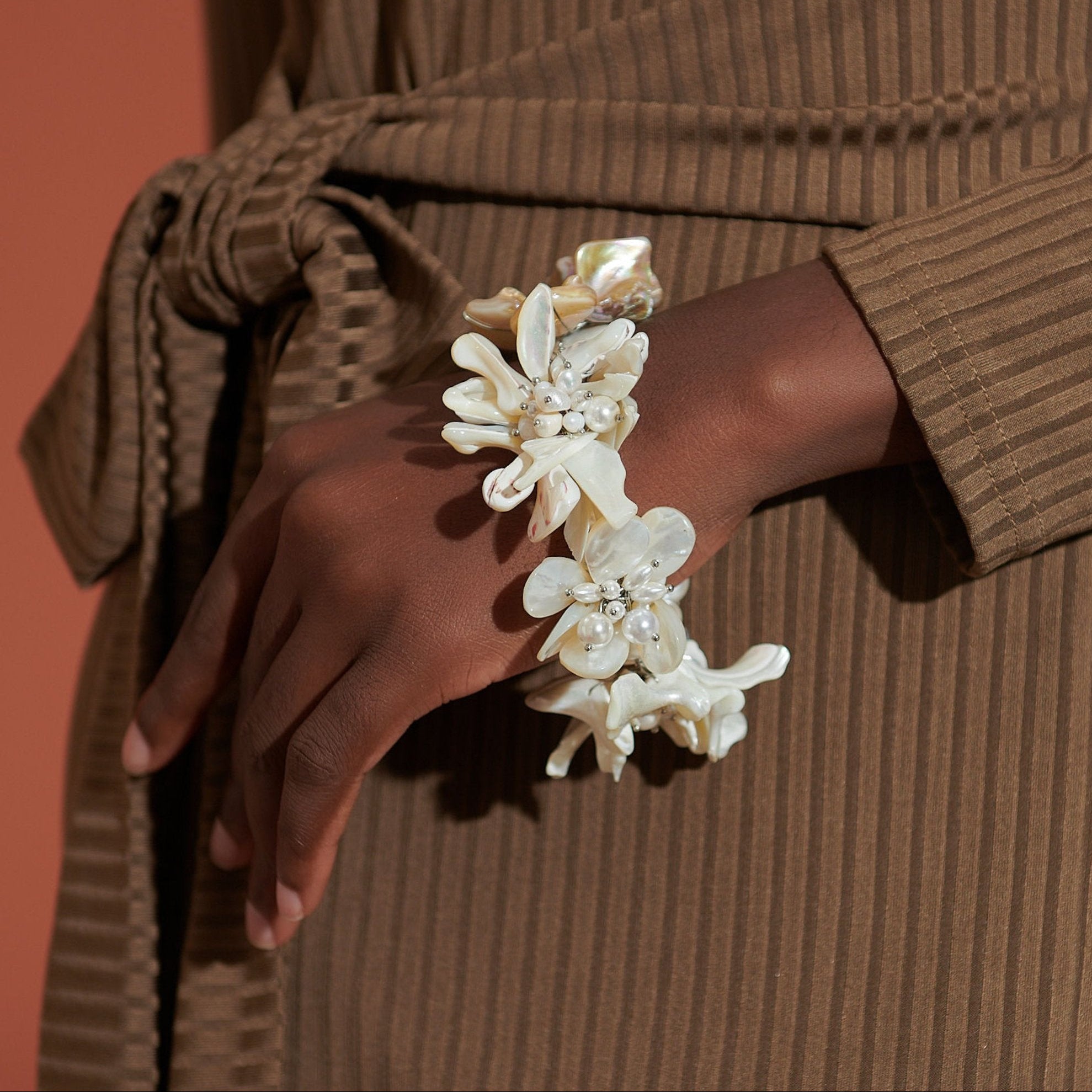 Mother of pearl floral statement bracelet with pearl cluster centers inspired by wisteria blossoms worn on a woman's wrist