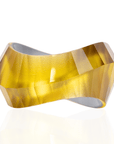 Faceted translucent golden resin bangle bracelet with sculptural modern shape on a white background.